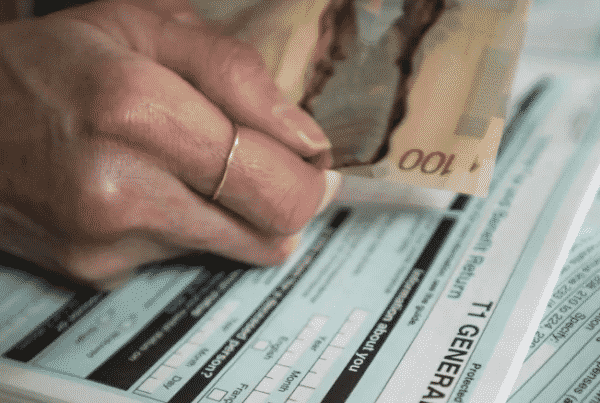 person filling out T1 tax form holding Canadian money