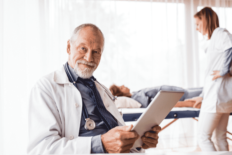 older medical doctor reviewing charts on a tablet