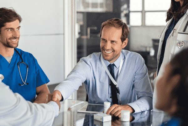hospital manager shaking hands with doctor across the table with other doctors in the room