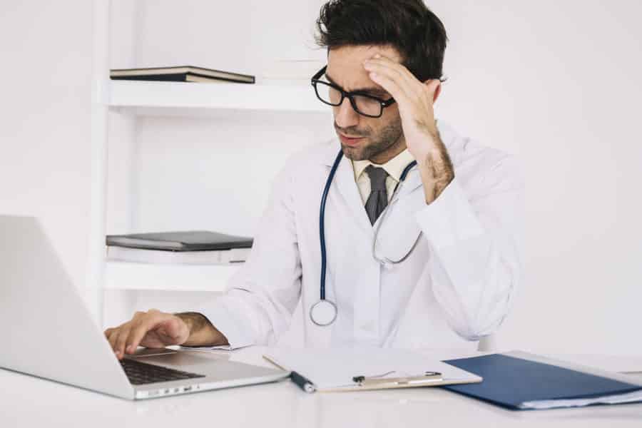 tired male doctor working on a laptop in a clinic